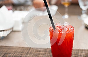 Strawberry lemonade pouring in glass from jug. Cocktail with strawberry, ice and mint in glasses on white concrete background,