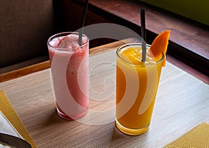 Strawberry mango shake on wooden table. Orange and pink fruit shake photo. Refreshing fruit drink. Vegetarian dessert