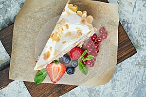 Strawberry meringue cake with almond petals, on newspaper