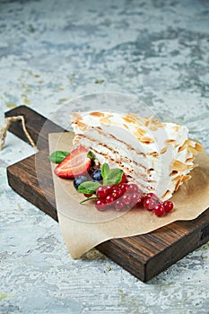 Strawberry meringue cake with almond petals, on newspaper