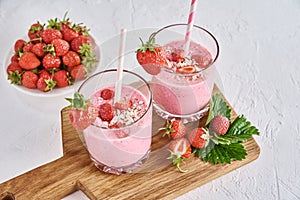 Strawberry milk shake in glass with straw and fresh berries on a white background