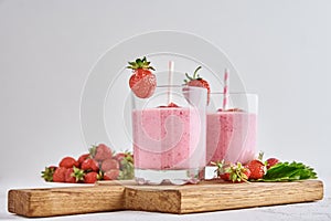 Strawberry milk shake in glass with straw and fresh berries on a white background