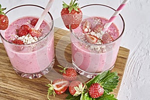 Strawberry milk shake in glass with straw and fresh berries on a white background