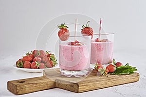 Strawberry milk shake in glass with straw and fresh berries on a white background