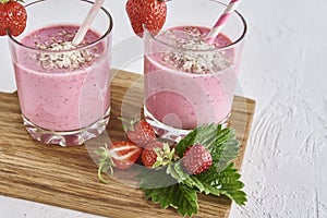 Strawberry milk shake in glass with straw and fresh berries on a white background