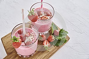 Strawberry milk shake in glass with straw and fresh berries on a white background