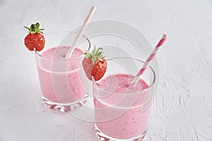 Strawberry milk shake in glass with straw and fresh berries on a white background