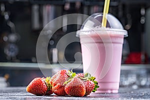 Strawberry milk shake to take away with straw on a dark background