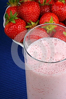 Strawberry milkshake and fruits over blue