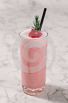 Strawberry milkshake with rosemary on white marble background.