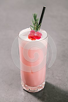 Strawberry milkshake with rosemary on white marble background.