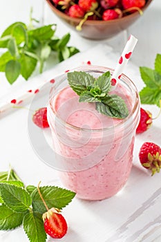Strawberry milkshake or smoothie on a white wooden background.