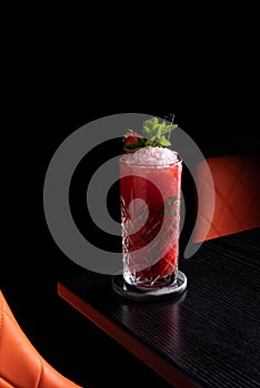 Strawberry mojito in dark moody bar garnished with mint