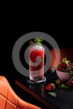 Strawberry mojito in dark moody bar garnished with mint