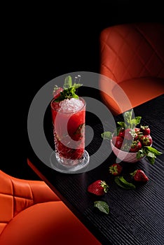 Strawberry mojito in dark moody bar garnished with mint