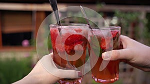 Strawberry mojito homemade alcoholic mixed drink, woman and man pair clinking glasses, cheers, chin chin