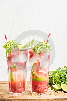 Strawberry mojito summer cocktails with mint and lime in tall glasses