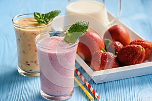 Strawberry and peach milkshakes on blue background.