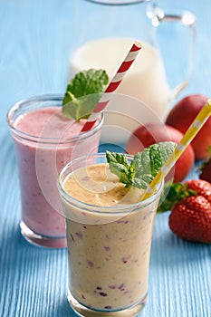 Strawberry and peach milkshakes on blue background.