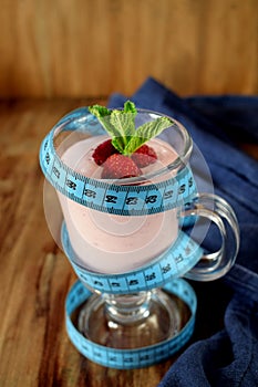 Strawberry protein cocktail decorated with berries and mint in an Irish mug wrapped into a blue measure tape.