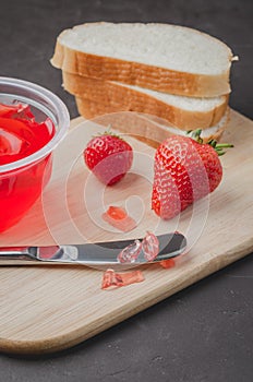 Strawberry pudding. Bread and strawberry pudding on a dark table with jar of pudding and fresh strawberry