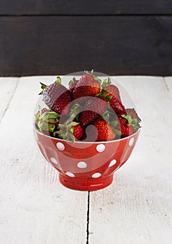 Strawberry in red bowl with a pattern in peas on a white table