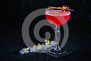 Strawberry Red Clover Club alcoholic cocktail with gin and vermouth decorated with flowers on black