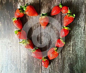 Strawberry red  heart-shaped  on wooden background table top wicker basket