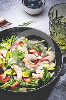 Strawberry, shrimp and herbs salad with arugula, lettuce, avocado and almond slices, gray table. Fresh useful dish for healthy