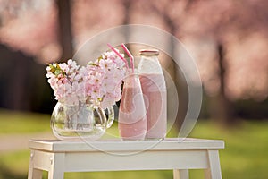 Strawberry smoothie freshly made in a jar, forest spring flowers