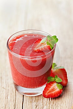 Strawberry smoothie in a glass decorated with mint leaves on rustic background, fresh fruit juice, detox food