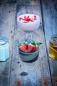 Strawberry smoothie in a glass with fresh strawberries, honey and yogurt