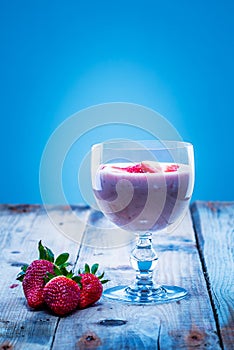 Strawberry smoothie in a glass with fresh strawberries