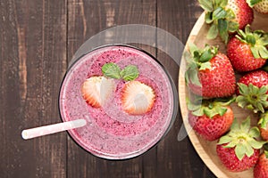 Strawberry smoothie in glass and fresh strawberries on wooden ba