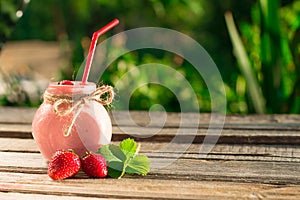 Strawberry smoothie in glass jar, over wood table.