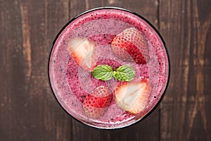 Strawberry smoothie in glass on wooden background