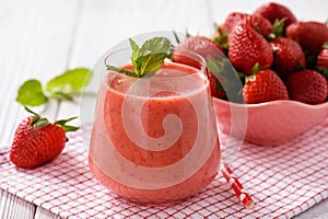 Strawberry smoothie in glass on wooden background.