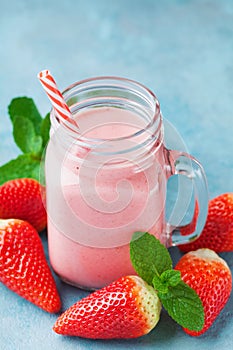 Strawberry smoothie or milkshake in mason jar on blue table. Healthy food for breakfast and snack.