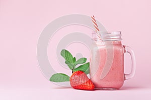 Strawberry smoothie or milkshake in mason jar decorated mint on pink table. Healthy food for breakfast and snack.