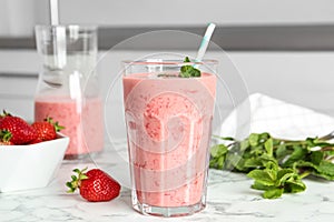 Strawberry smoothie with mint in glass on white marble table