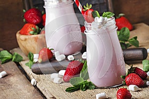 Strawberry smoothies and cocktails with fresh berry and green mint, decorated marshmallows, summer drink, wood old background,
