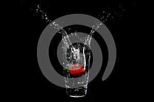 Strawberry splash inside a glass of water - black background - high speed photography