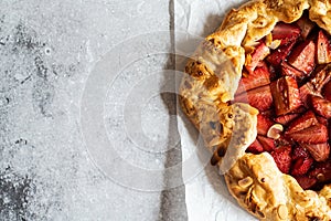 Strawberry summer galette with puf pastry and almond flakes on gray background. Copy space