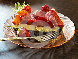 Strawberry tart cake with cream filling on a glass plate with folk