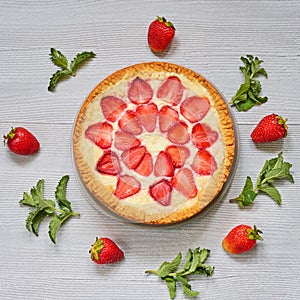 Strawberry tart on the gray kitchen background. Berries cheesecake decorated with organic fresh strawberries and mint