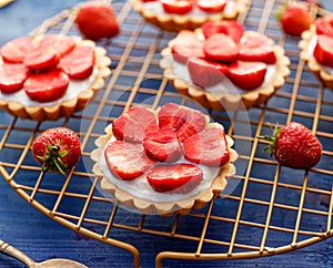 Strawberry tarts, small shortbread tarts with the addition of cream cheese, fresh strawberries  on a cooling tray