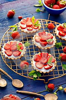 Strawberry tarts, small shortbread tarts with the addition of cream cheese, fresh strawberries  on a cooling tray