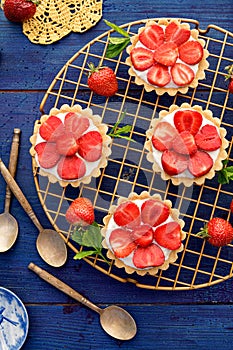 Strawberry tarts, small shortbread tarts with the addition of cream cheese, fresh strawberries and mint on cooling tray