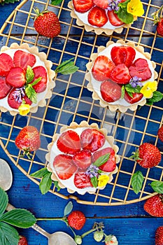Strawberry tarts, small shortbread tarts with the addition of cream cheese, fresh strawberries and mint on cooling tray