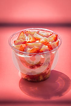Strawberry tiramisu custard dessert in a glass with fresh strawberry on a rose abstract background.